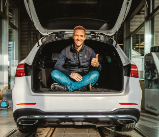 Schloz Wöllenstein Mitarbeiter sitzt im Kofferraum eines Mercedes-Benz PKW